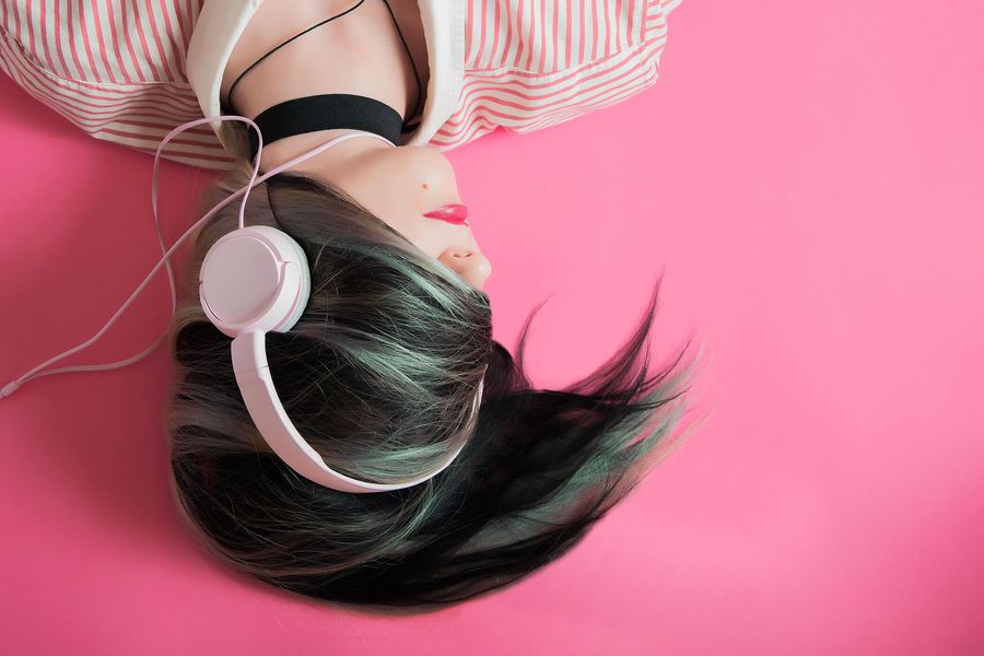 Auditrice avec un casque audio sur fond rose